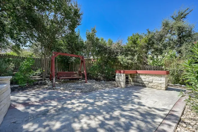 a view of a park with large trees and wooden fence