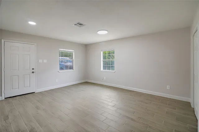 an empty room with wooden floor and windows