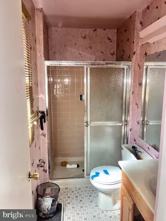 a bathroom with a granite countertop sink a toilet a mirror and shower