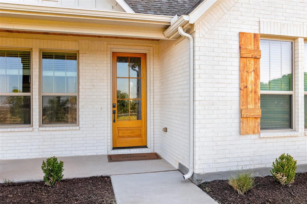 10828 Gregory Road Sanger, TX 76266 - Photo 6 of 37 White painted brick exterior with a wood-panel front door