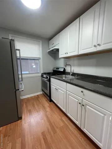 a kitchen with granite countertop white cabinets and black appliances