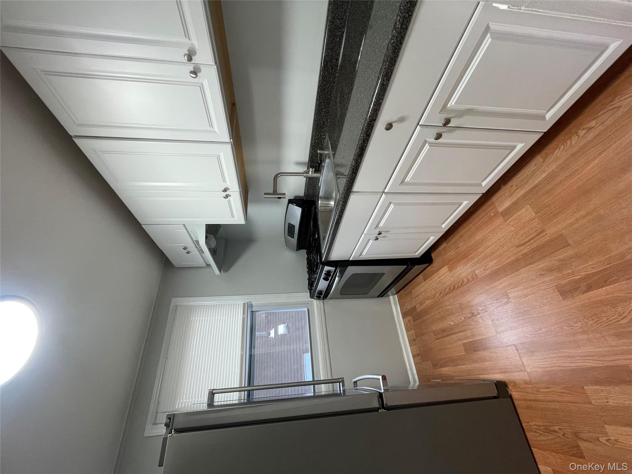 129-38 154th Street Queens, NY 11434 - Photo 9 of 10 a kitchen with granite countertop white cabinets and black appliances