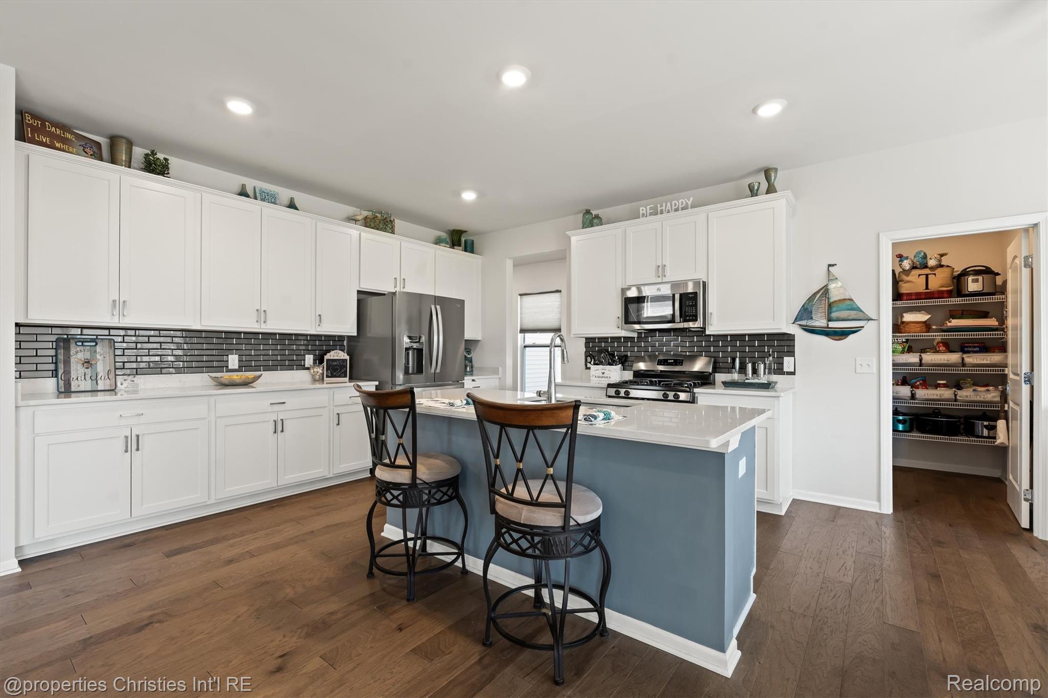 2721 Maize Loop Saline, MI 48176 - Photo 11 of 52 Kitchen with stainless steel appliances, a breakfast bar, white cabinetry, an island with sink, and dark wood-type flooring