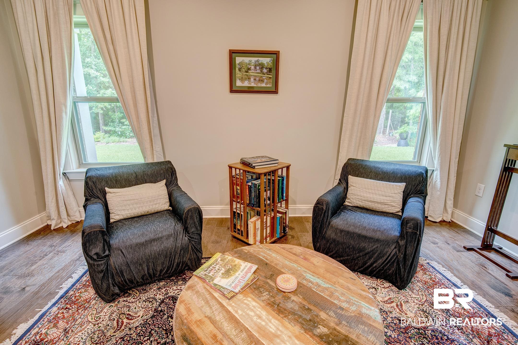 18754 Treasure Oaks Road Gulf Shores, AL 36542 - Photo 16 of 53 Bright room featuring two large windows with drapes, wood-finish flooring, and a decorative area rug