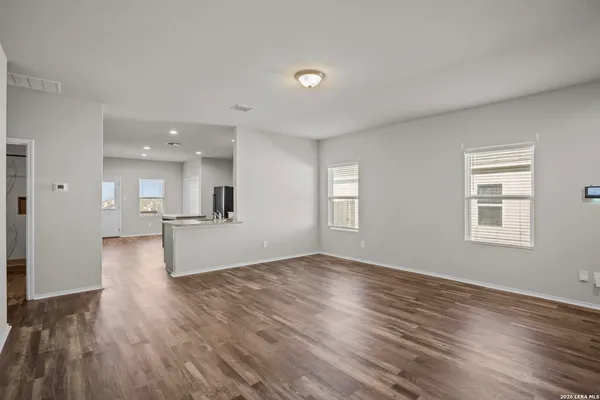 a view of kitchen and empty room with wooden floor and windows