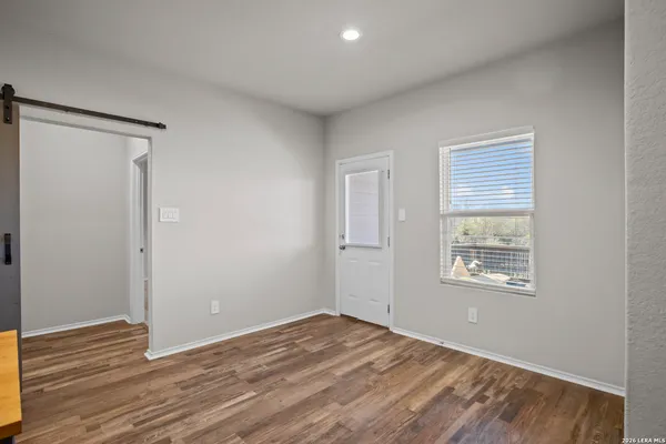 a view of an empty room with wooden floor and a window
