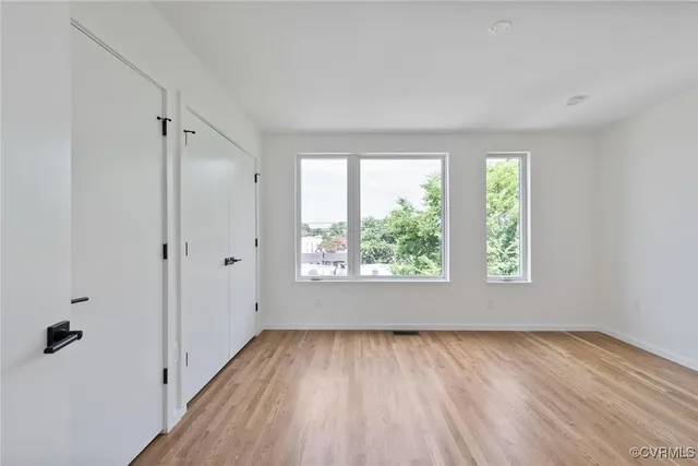 an empty room with wooden floor and windows