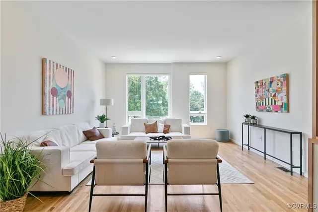 a living room with furniture two windows and a dining table