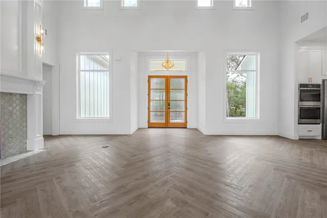 a view of an empty room with a window and kitchen view