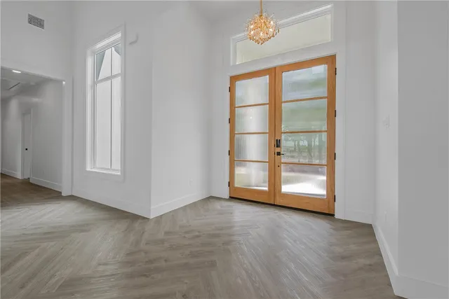 an empty room with wooden floor cabinet and windows