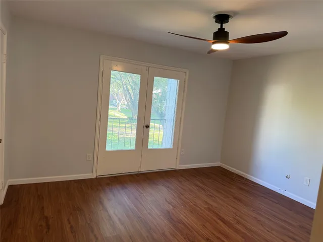an empty room with wooden floor fan and windows