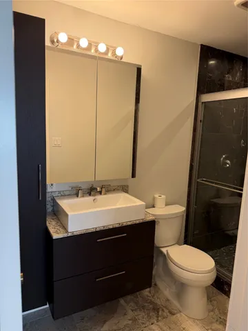 a bathroom with a sink vanity mirror and toilet