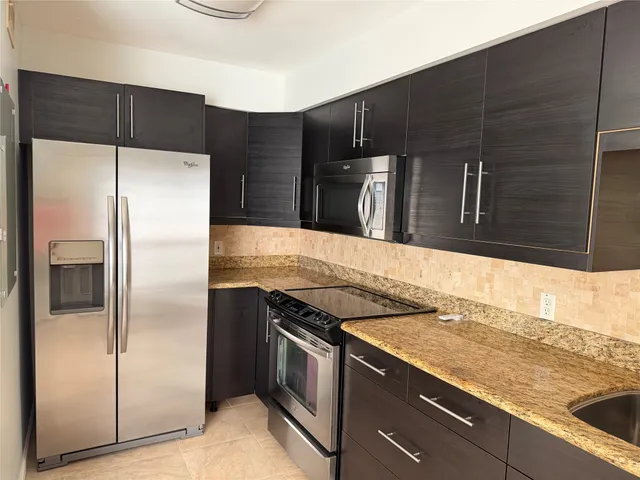 a kitchen with granite countertop a refrigerator and a sink