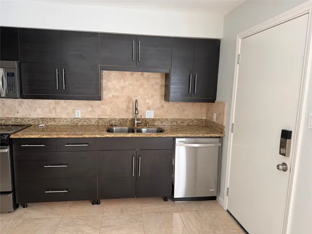 a kitchen with granite countertop a sink cabinets and stainless steel appliances