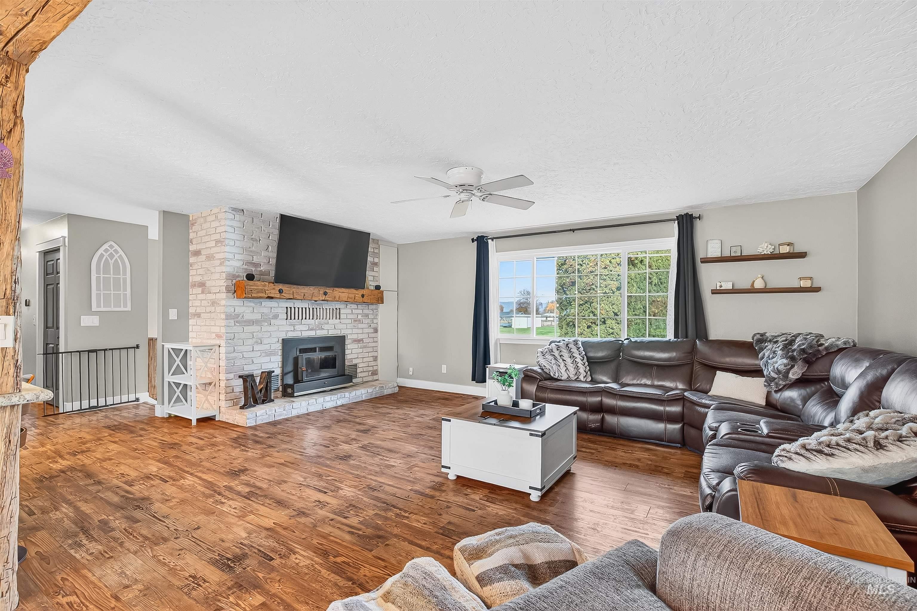 1220 Birch Avenue Lewiston, ID 83501 - Photo 11 of 45 Living room with wood finished floors, a brick fireplace, a textured ceiling, and a ceiling fan