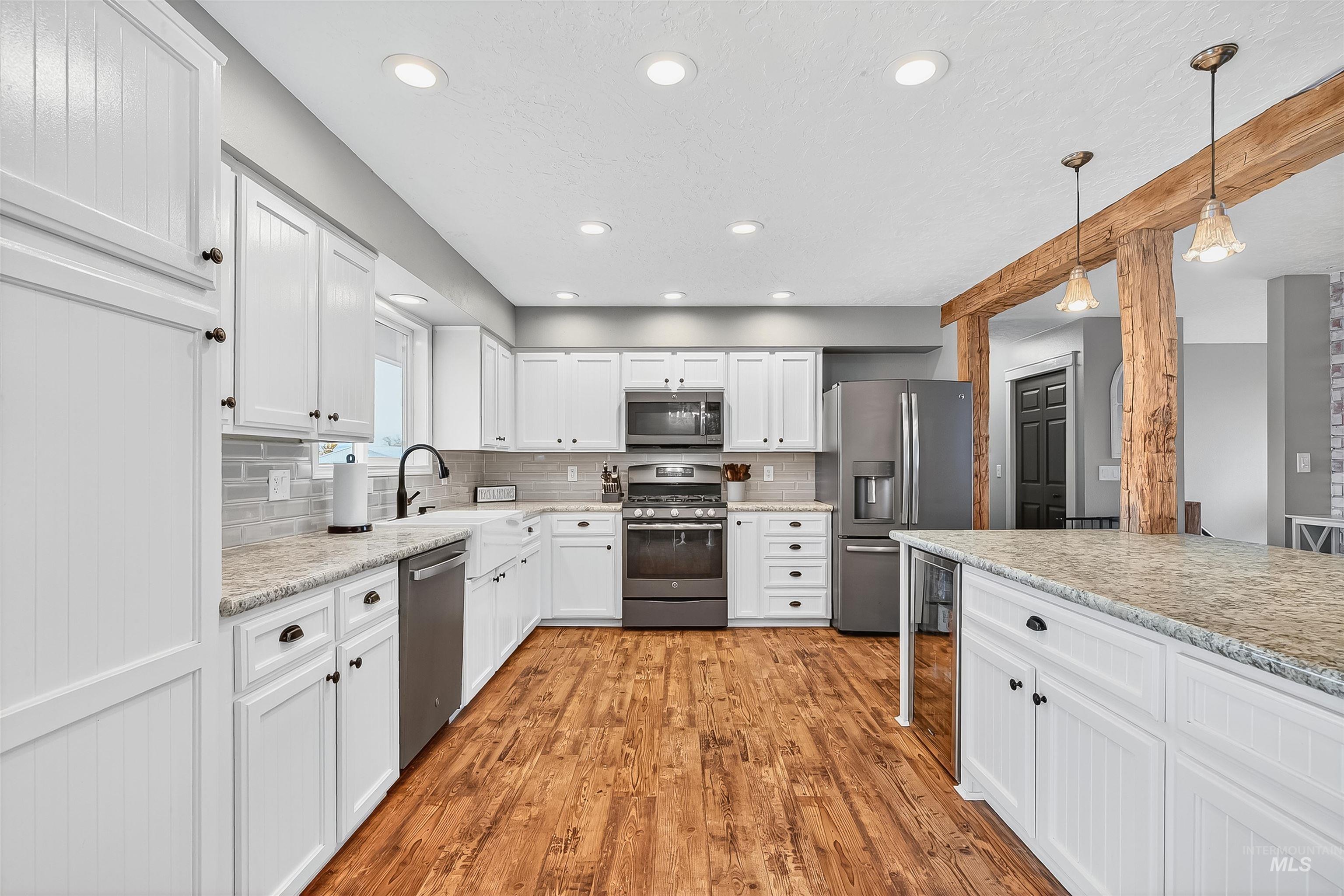 1220 Birch Avenue Lewiston, ID 83501 - Photo 5 of 45 Kitchen featuring white cabinets, stainless steel appliances, light wood-style floors, decorative light fixtures, and tasteful backsplash