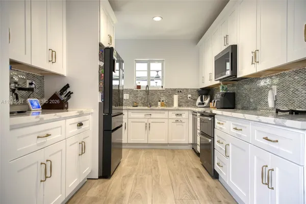 a kitchen with white cabinets stainless steel appliances and sink