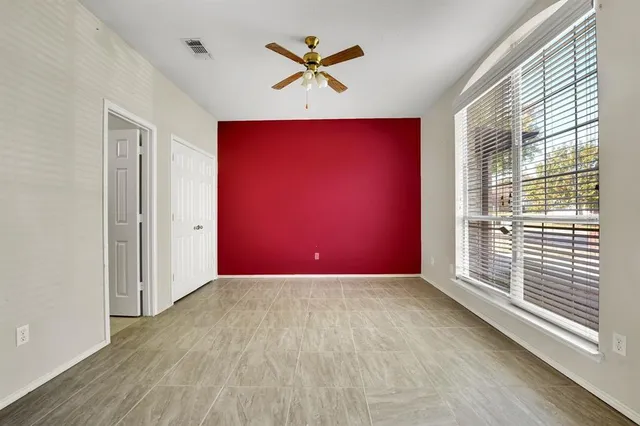 an empty room with windows and a ceiling fan