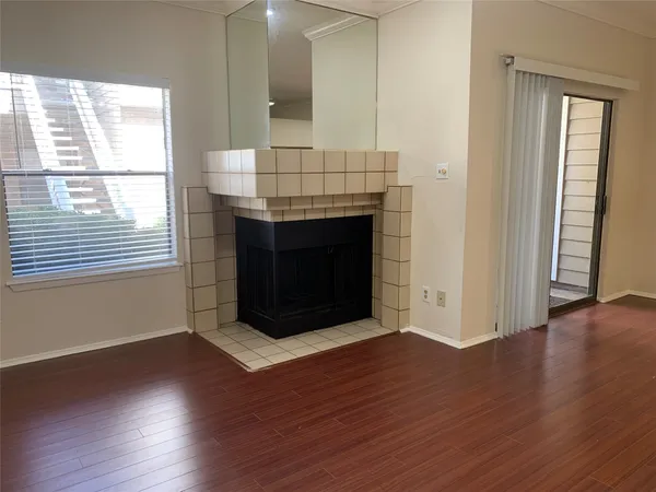 an empty room with wooden floor fireplace and windows