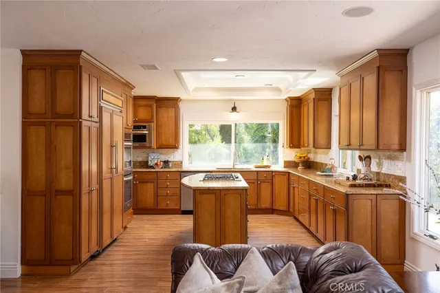 a kitchen with stainless steel appliances granite countertop a stove a sink dishwasher a refrigerator and a dining table with wooden floor