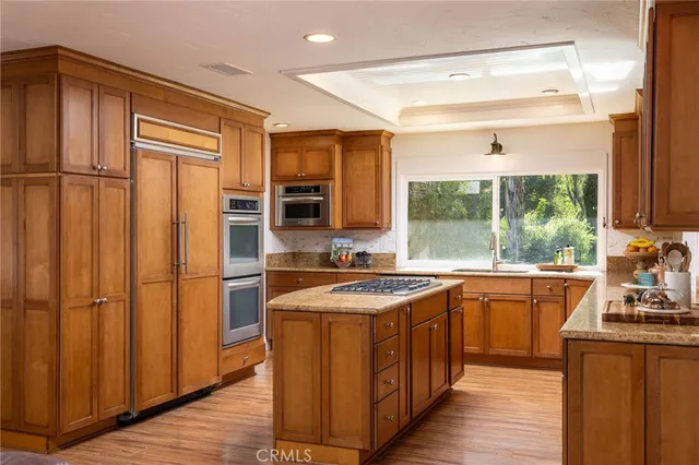 a kitchen with stainless steel appliances granite countertop a refrigerator a sink dishwasher a stove with wooden cabinets and floor