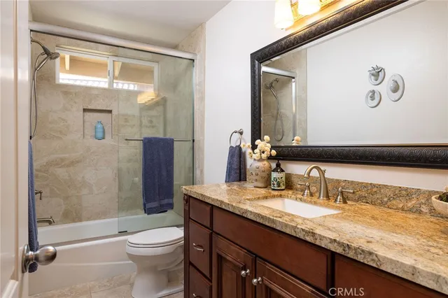 a bathroom with a granite countertop sink toilet and shower