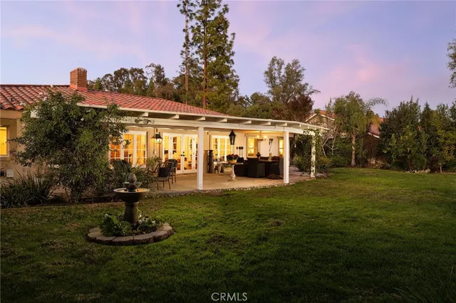 a front view of a house with garden and trees