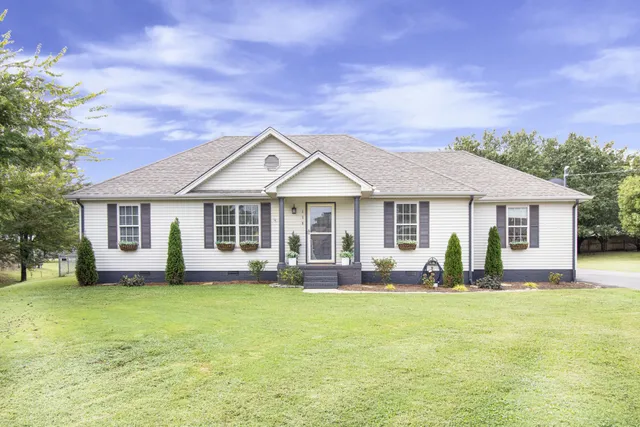 a front view of a house with a garden and trees