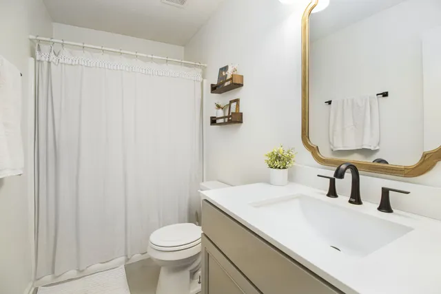 a bathroom with a sink a toilet and shower curtain