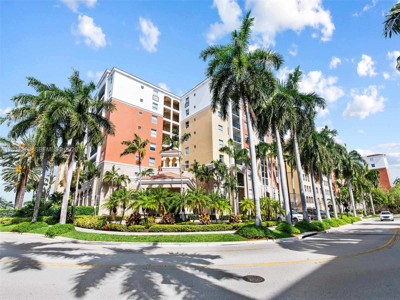 a front view of multi story residential apartment building with yard and green space
