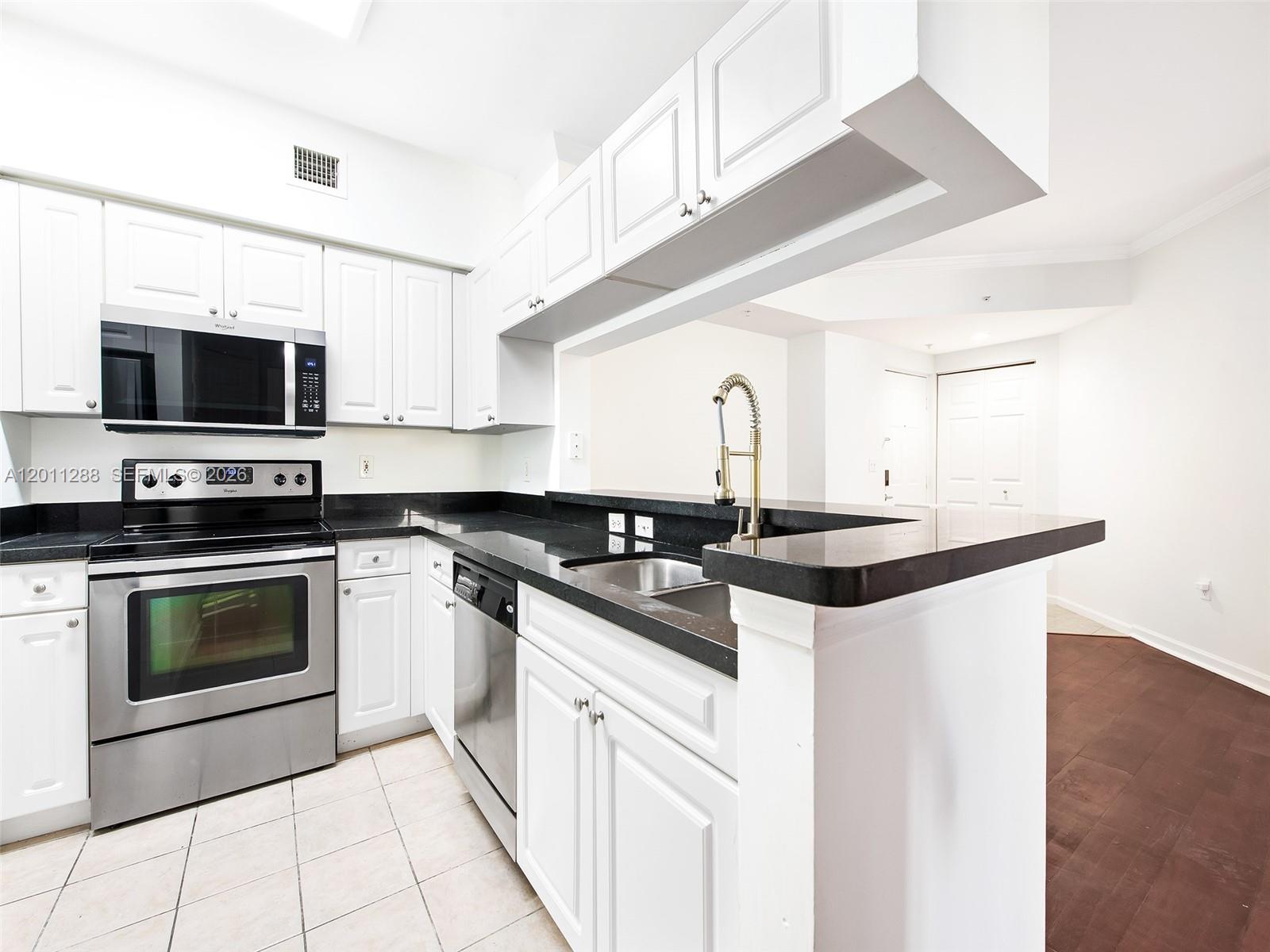 17100 North Bay Road, Unit 1614 Sunny Isles Beach, FL 33160 - Photo 7 of 17 a kitchen with stainless steel appliances a stove a sink and a microwave