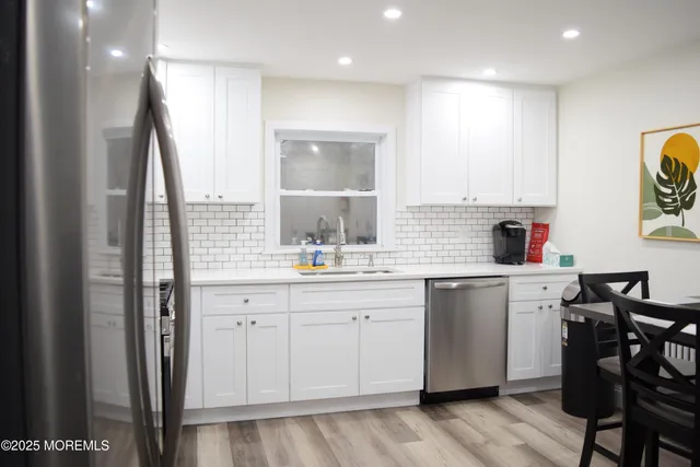 a kitchen with a sink dishwasher a dining table and chairs with wooden floor