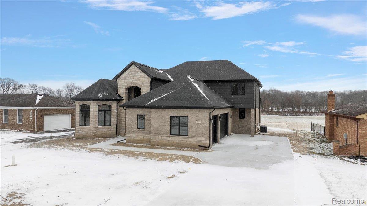 53650 Romeo Plank Road Macomb, MI 48042 - Photo 4 of 64 French country inspired facade with brick siding, stone siding, and a garage