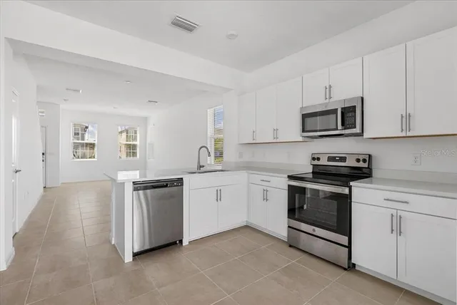 a kitchen with granite countertop white cabinets and stainless steel appliances