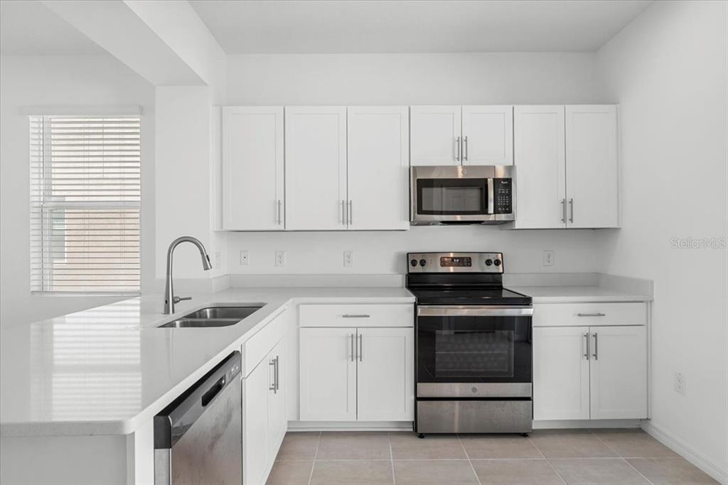 6338 Fairmont Lane Palmetto, FL 34221 - Photo 26 of 39 a kitchen with white cabinets and stainless steel appliances