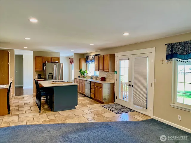 a large kitchen with stainless steel appliances kitchen island granite countertop a large window and a refrigerator