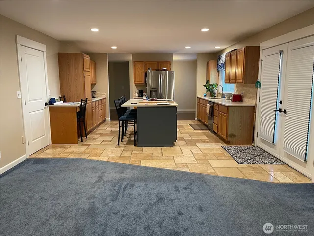 a living room with stainless steel appliances kitchen island granite countertop a couch and a view of kitchen