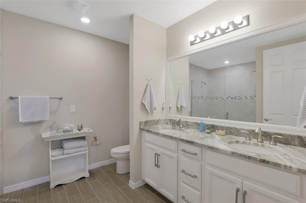 14663 Edgewater Circle Naples, FL 34114 - Photo 15 of 35 a bathroom with a granite countertop double vanity sink a toilet and a mirror