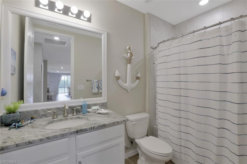14663 Edgewater Circle Naples, FL 34114 - Photo 17 of 35 a bathroom with a granite countertop sink a toilet and mirror
