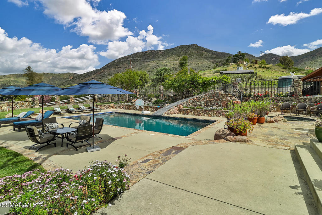 3030 Triunfo Canyon Road Agoura Hills, CA 91301 - Photo 13 of 50 a view of a swimming pool with lawn chairs under an umbrella