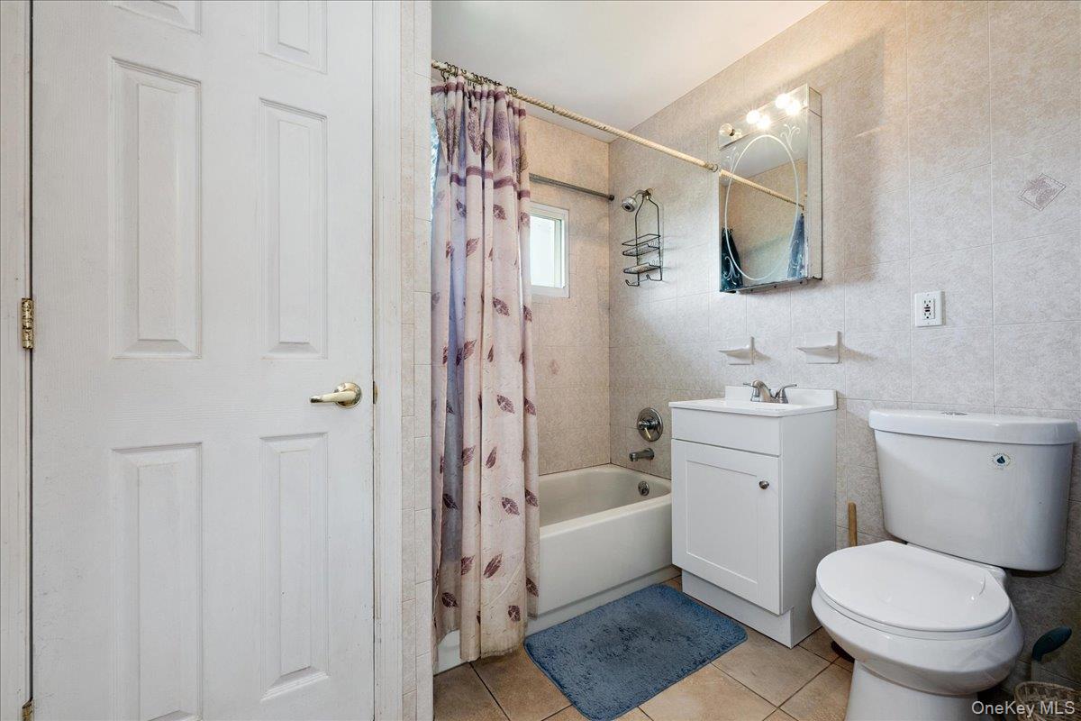 181 Springtime Lane North Levittown, NY 11756 - Photo 11 of 22 Bathroom featuring shower / tub combo, vanity, light tile patterned floors, and tile walls