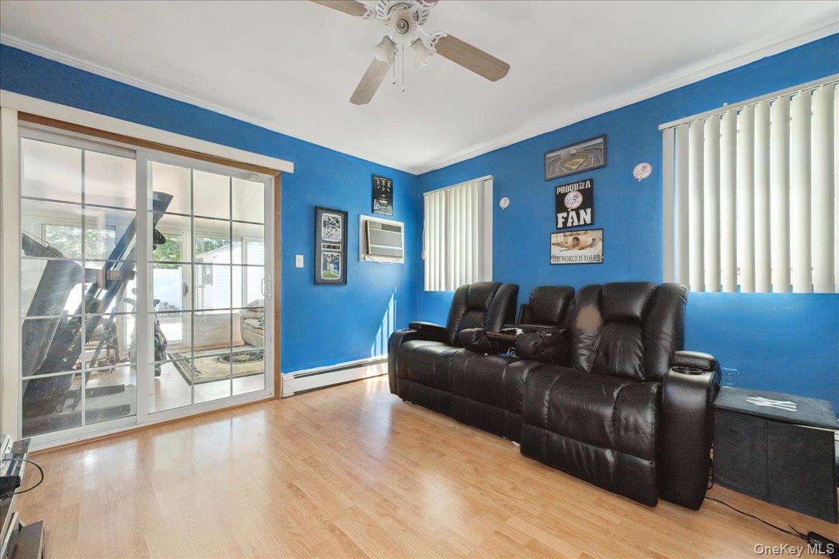 181 Springtime Lane North Levittown, NY 11756 - Photo 12 of 22 Living area featuring wood finished floors, a baseboard radiator, a wall mounted AC, and a ceiling fan
