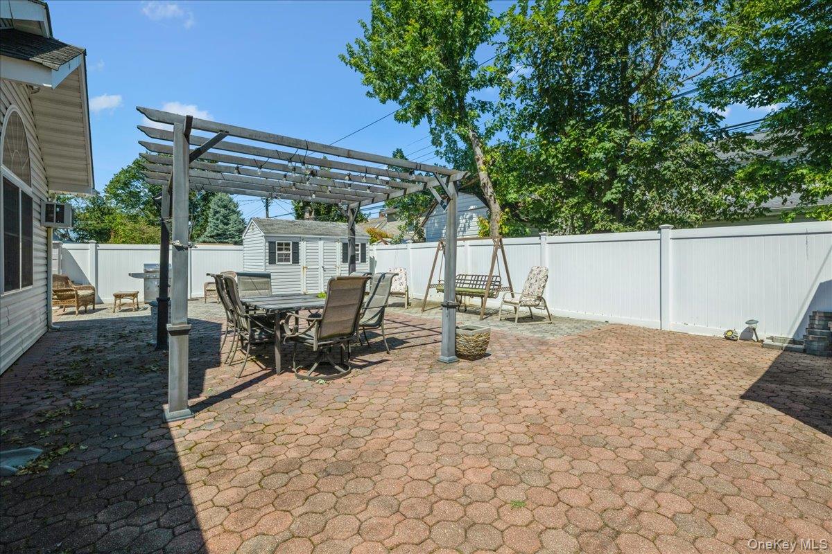 181 Springtime Lane North Levittown, NY 11756 - Photo 19 of 22 Fenced backyard with a pergola, a patio area, a shed, and outdoor dining area