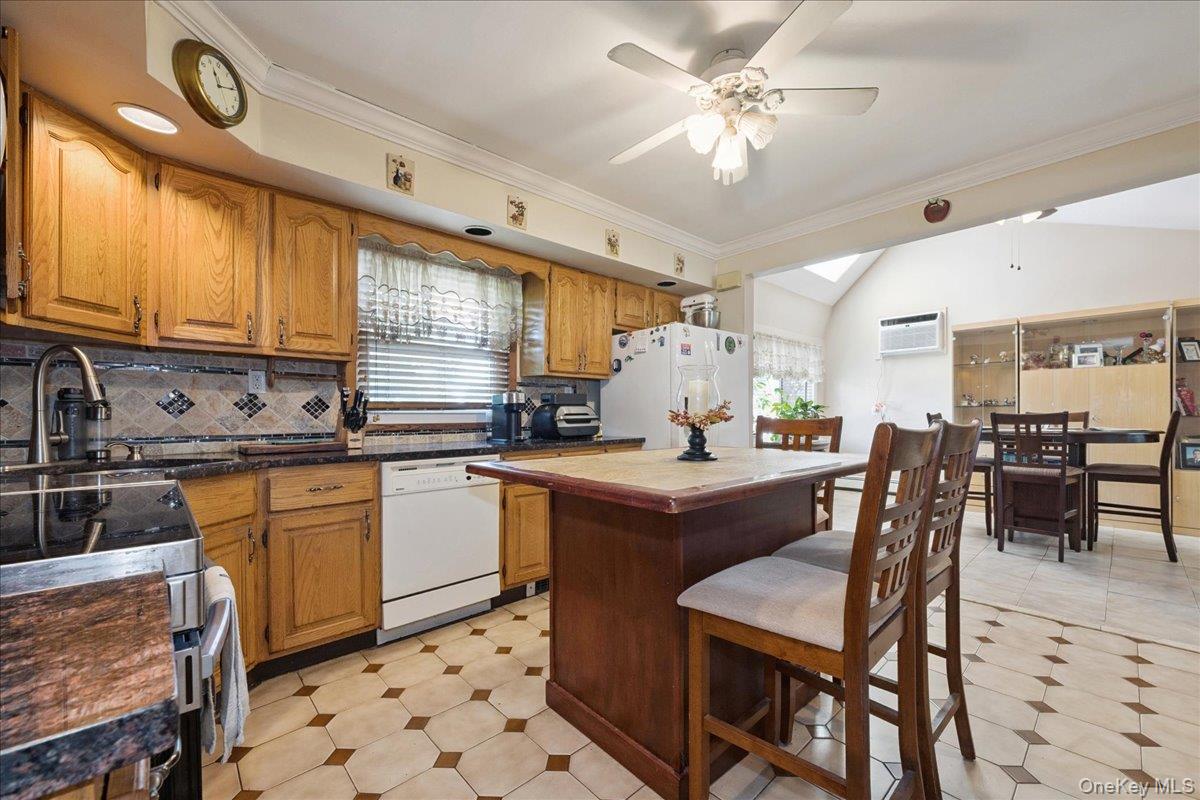 181 Springtime Lane North Levittown, NY 11756 - Photo 6 of 22 Kitchen featuring brown cabinetry, crown molding, white appliances, a center island, and decorative backsplash