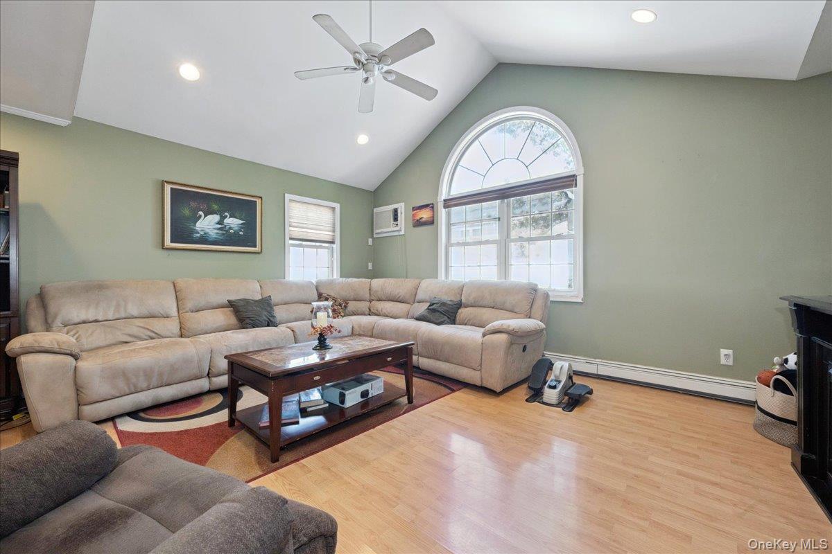 181 Springtime Lane North Levittown, NY 11756 - Photo 8 of 22 Living area featuring light wood-type flooring, high vaulted ceiling, baseboard heating, recessed lighting, and ceiling fan