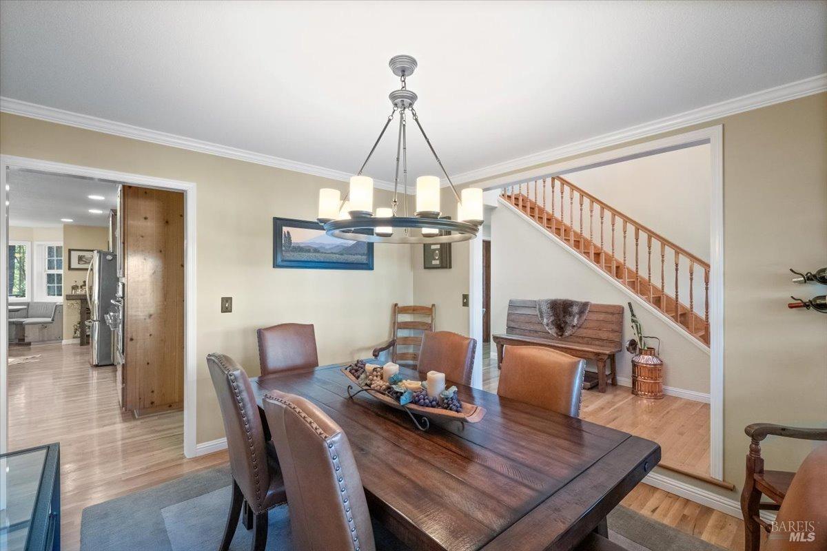 5701 Ridgewood Road Willits, CA 95490 - Photo 22 of 84 a dining room with wooden floor a chandelier a wooden table and chairs