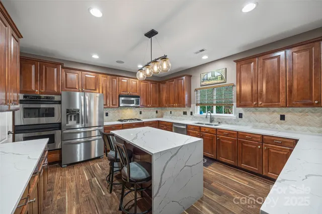 a kitchen with stainless steel appliances granite countertop a stove refrigerator sink and microwave