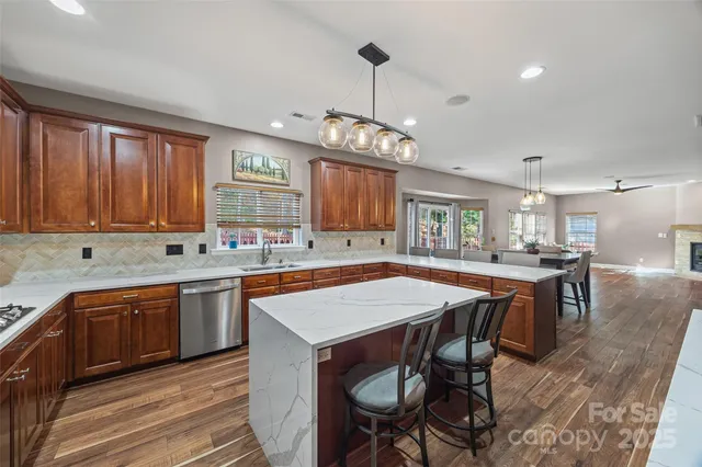 a kitchen with stainless steel appliances granite countertop a kitchen island hardwood floor sink stove dining table and chairs