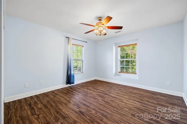 a view of an empty room with window and wooden floor