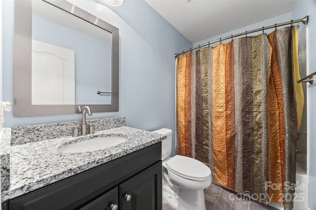 a bathroom with a granite countertop sink toilet and mirror